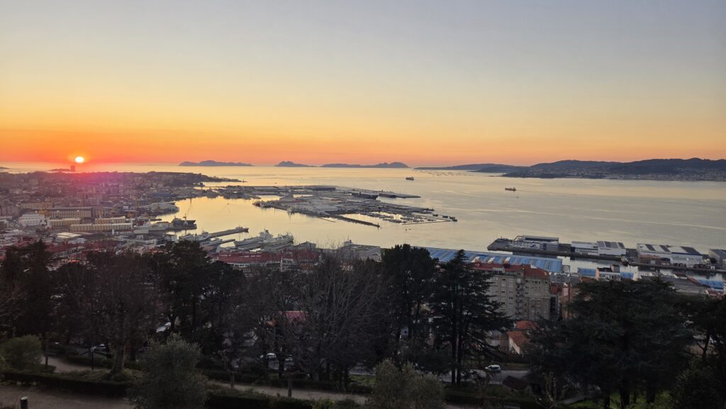 A lush view of Vigo Bay at sunset in Galicia, showcasing the scenic coastal landscape and vibrant ci.