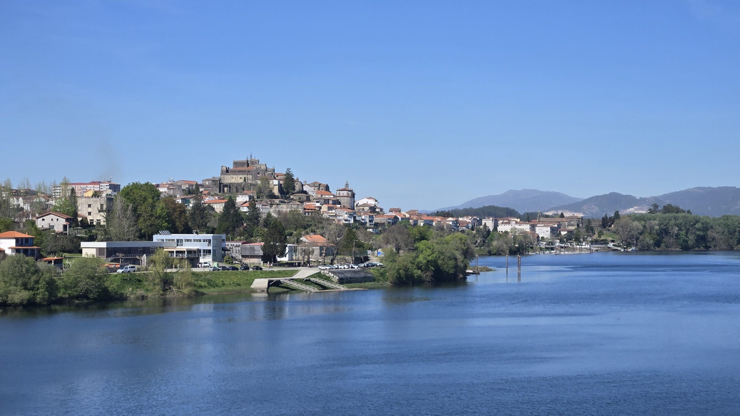 Scenic view of Galicia river with town and mountain backdrop in Galicia, Spain.
