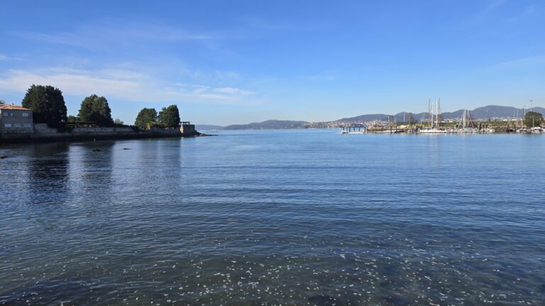 Beautiful coastal scene of Galicia with calm waters and sailboats.